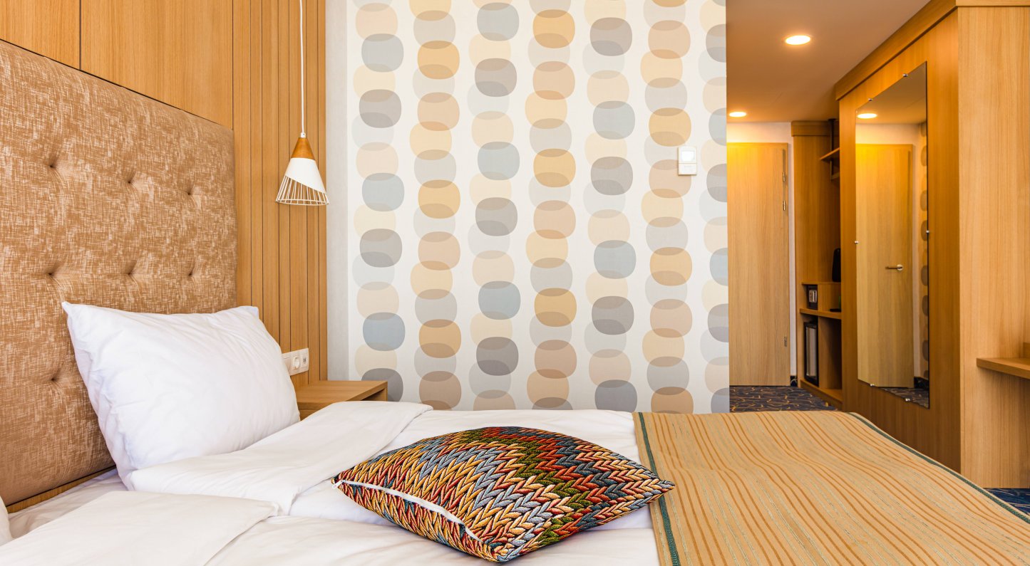 Guest room at Marina Burgas Hotel with wooden panelling and retro wallpaper